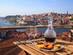 A glass bottle of port and plate of cakes on a table overlooking the river in Porto, Portugal