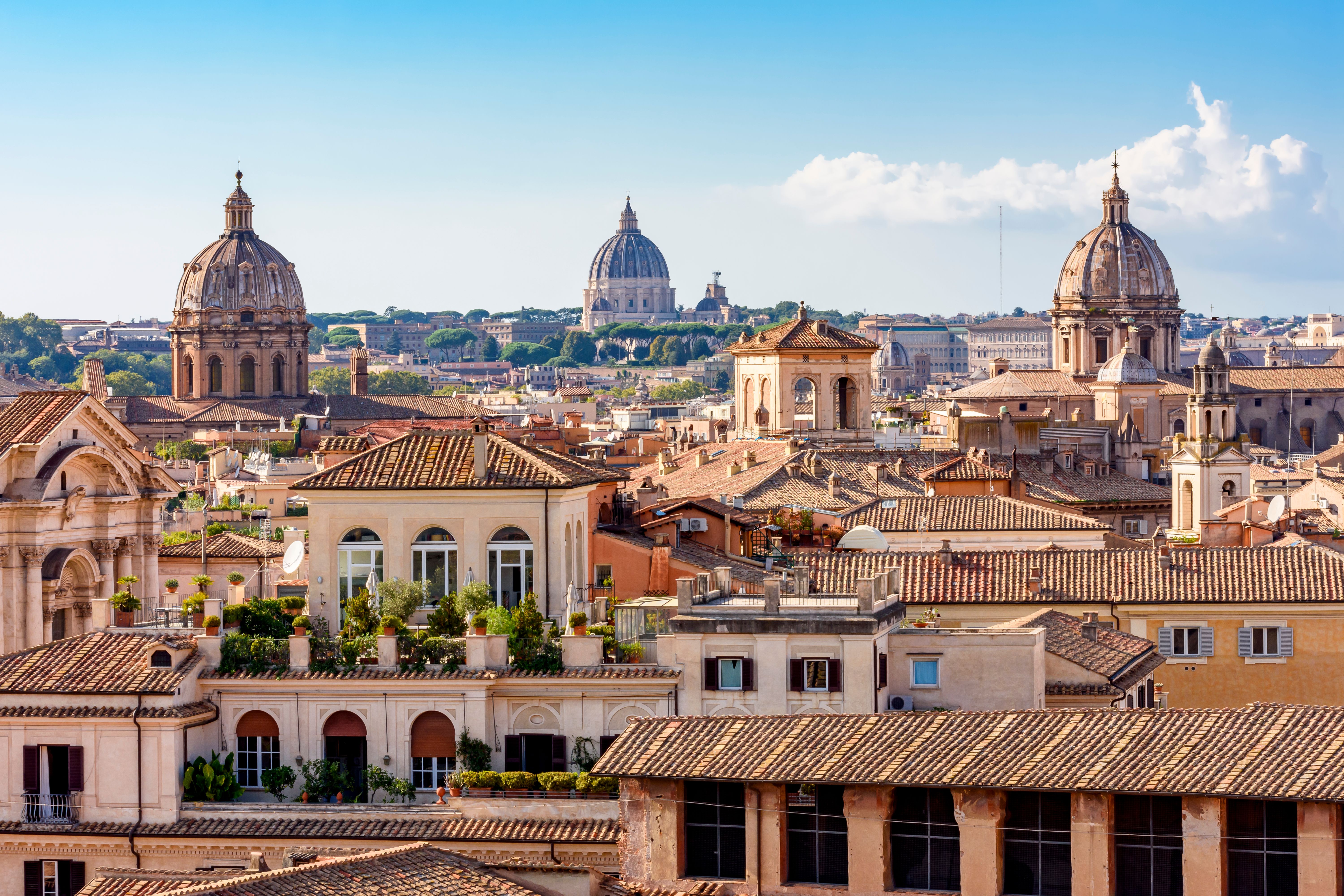 A view over the terracotta rooftops of Rome with the dome of St. Peter's Basilica in the background