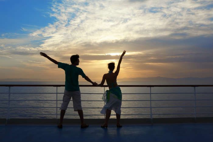 Couple with arms raised on cruise ship
