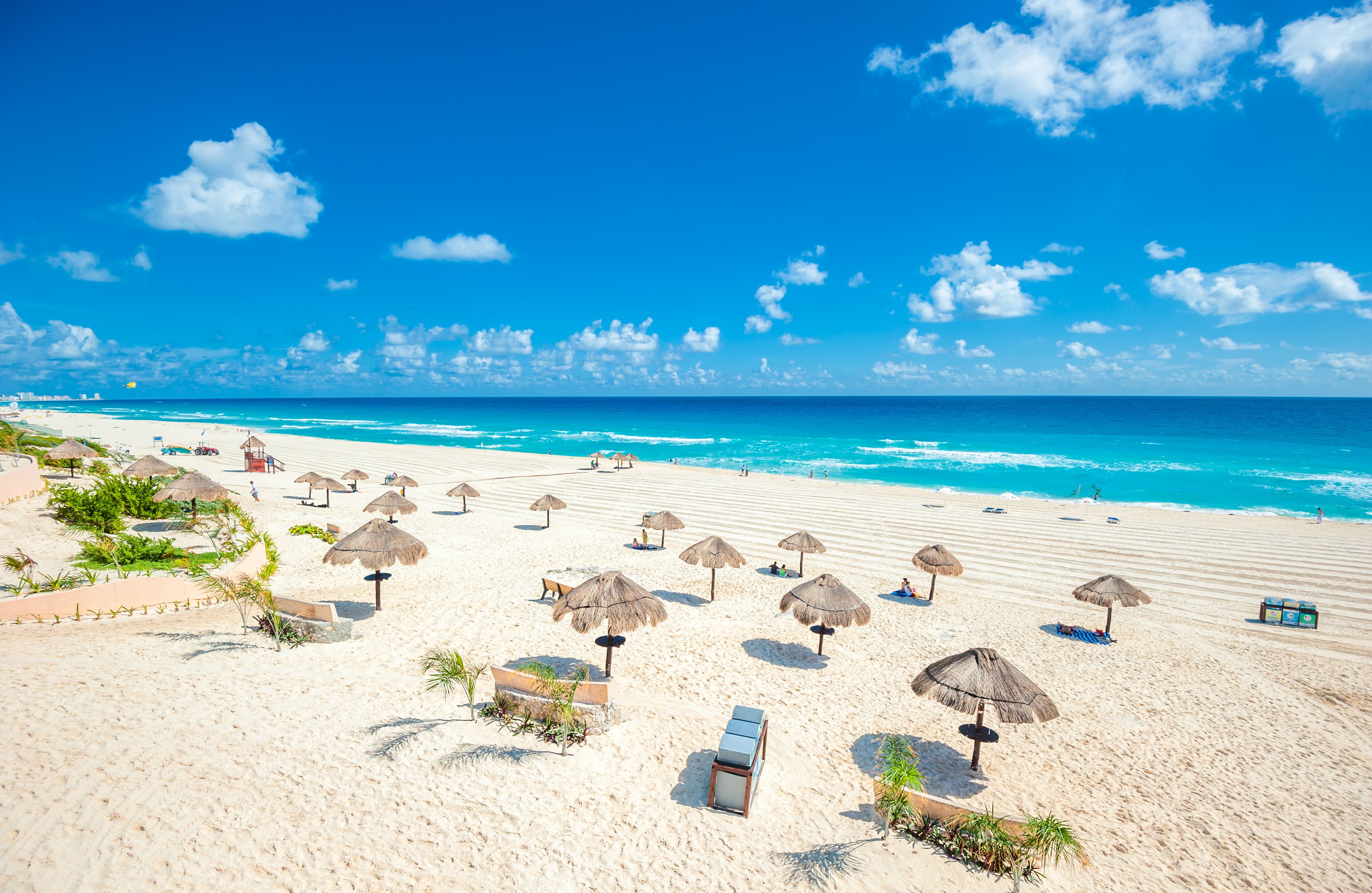 A white-sand beach with thatch umbrellas in Cancun, Mexico