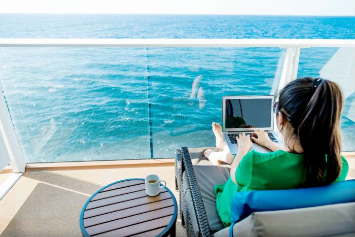 Woman using laptop on cruise cabin balcony