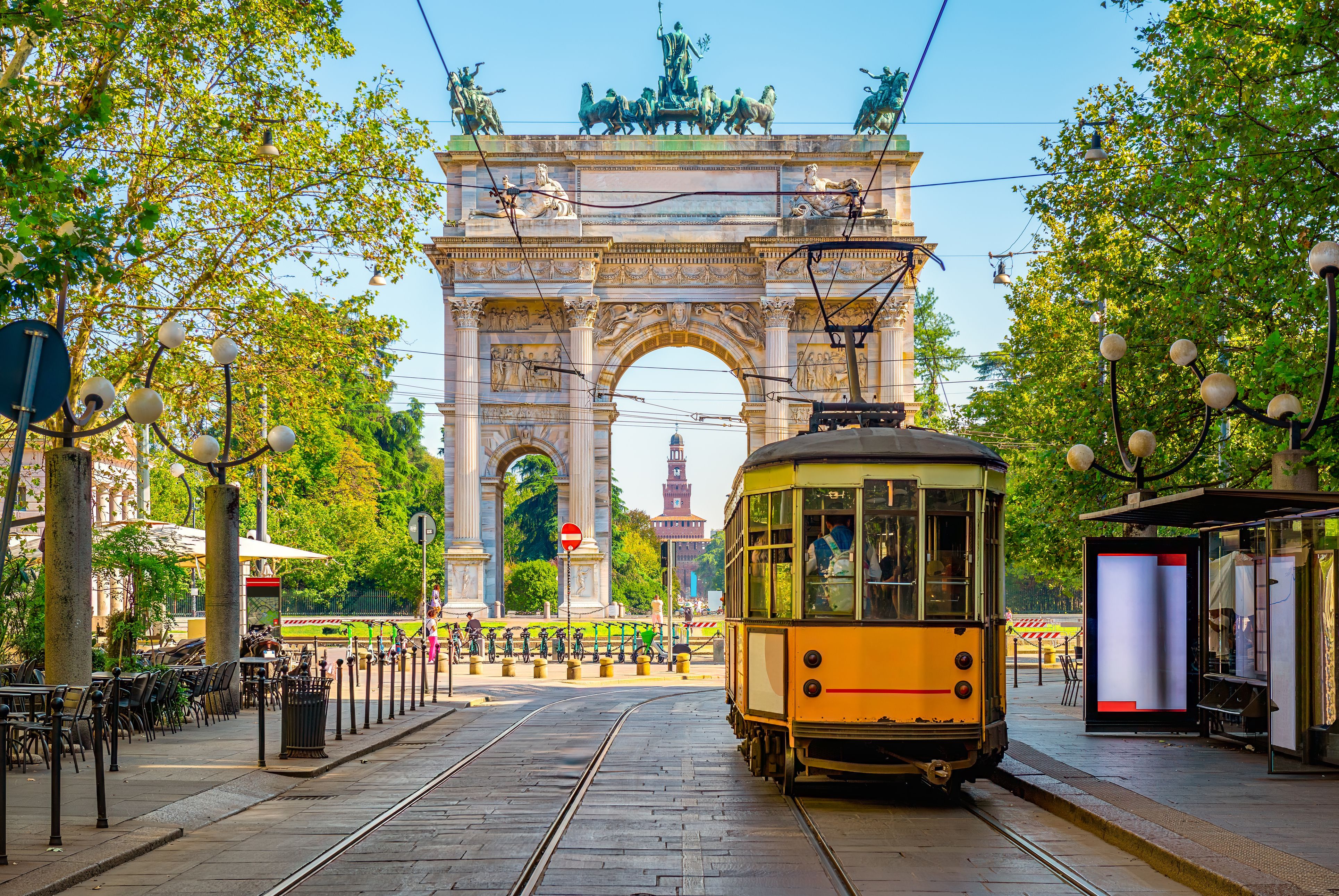 View of the Peace Arch as a yellow tram drives past in Milan, Italy