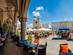 View from under the arches of the Cloth Hall of Krakow main square filled with restaurant tables on a sunny day