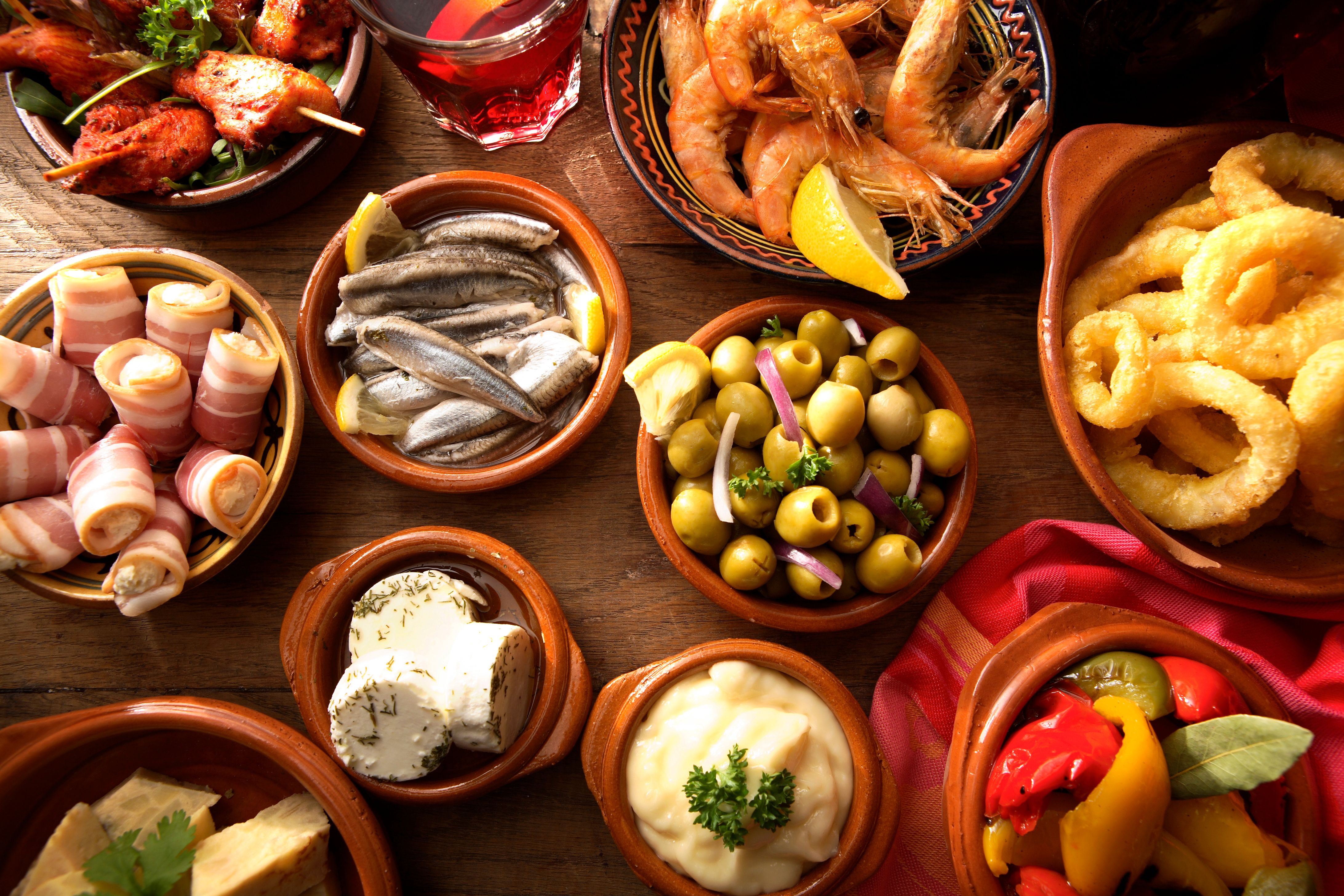 A bird's-eye-view shot of a variety of Spanish tapas dishes laid out on a table