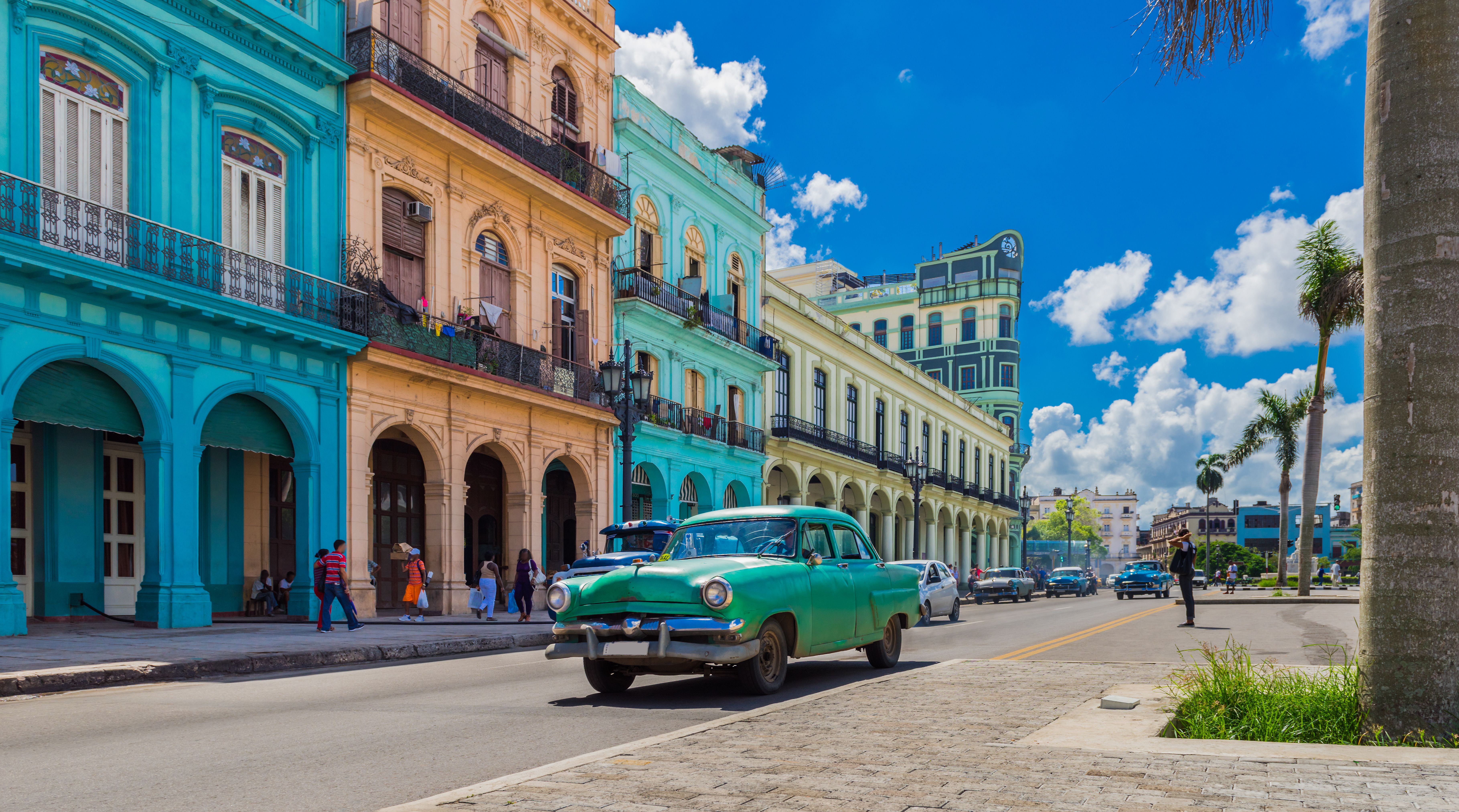 Cityscape with green vintage car on the main street in Havana city, Cuba