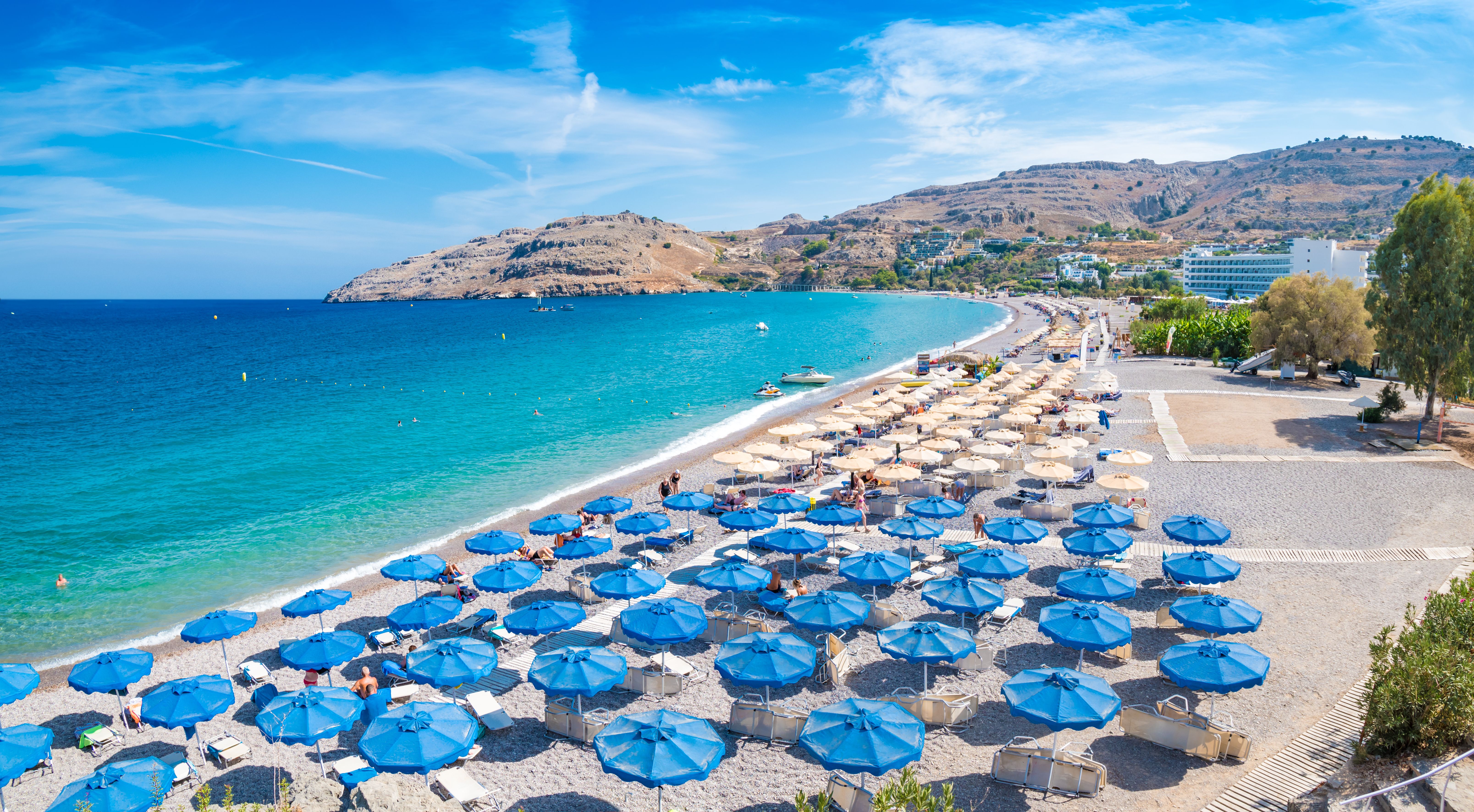 A view of umbrellas and sunbeams on Vlycha beach in Rhodes, Greece