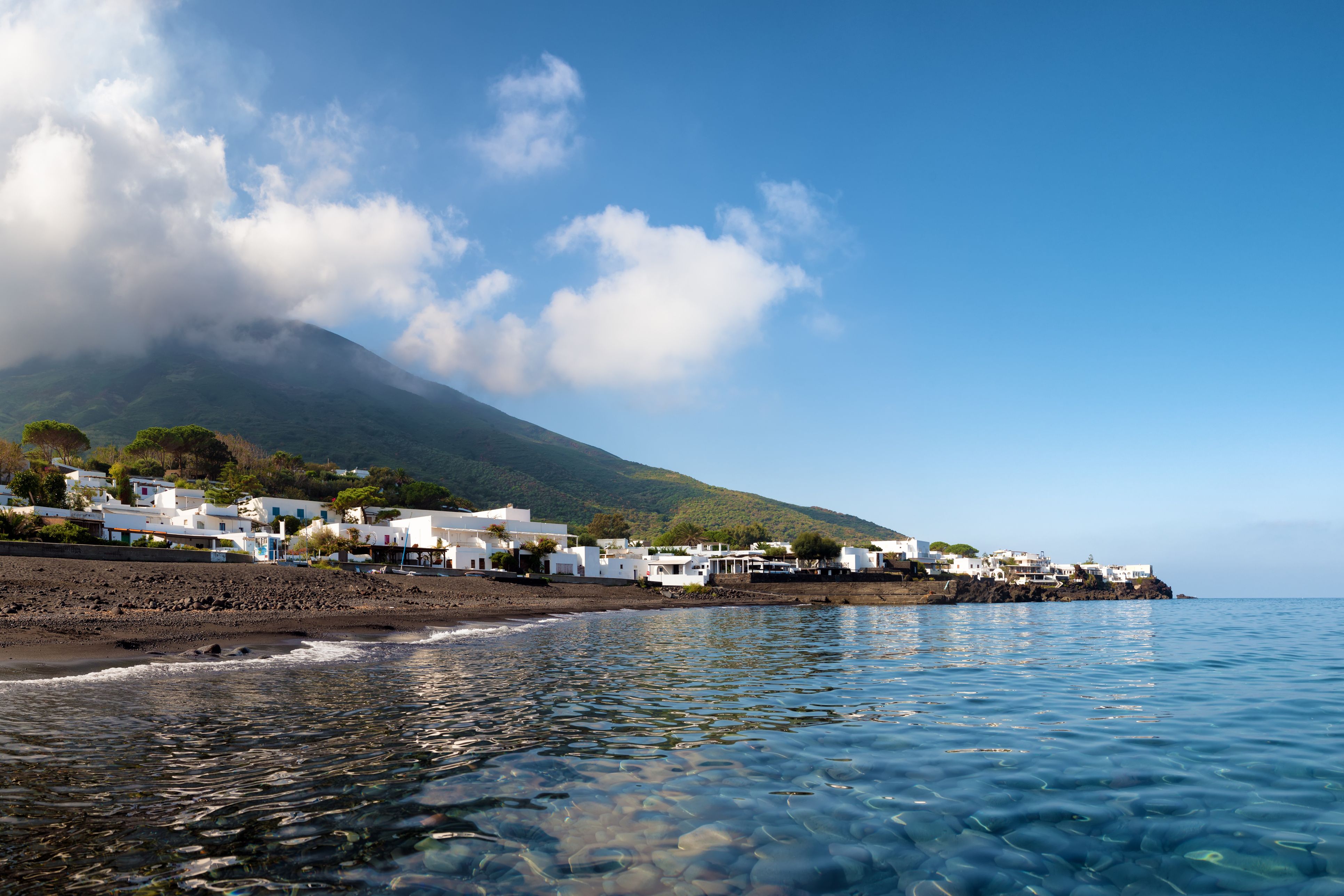 View of white houses beneath a steaming volcano on Stromboli island, Sicily