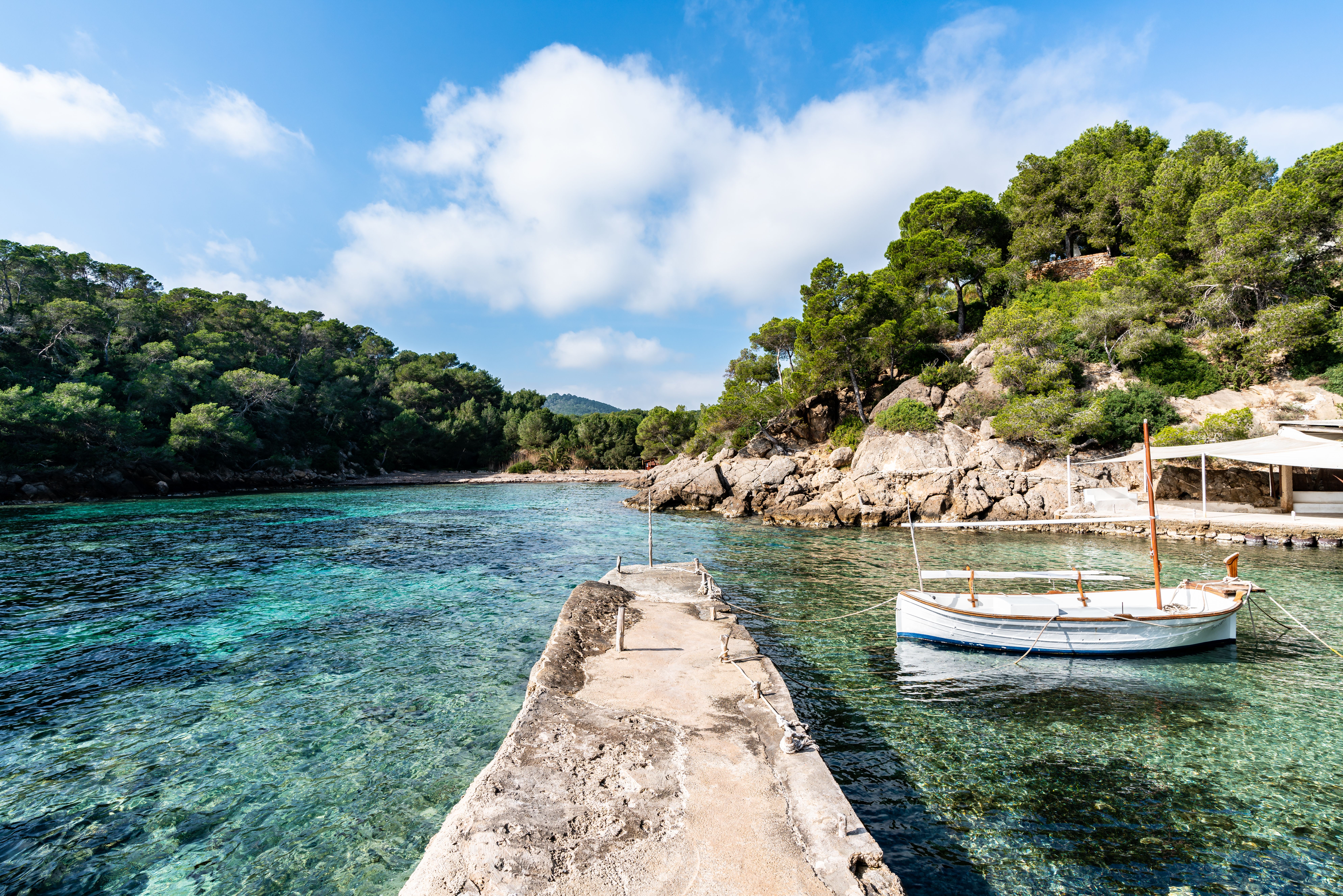 View of a concrete pier jutting into crystal-clear waters in a tranquil cove