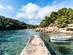 View of a concrete pier jutting into crystal-clear waters in a tranquil cove
