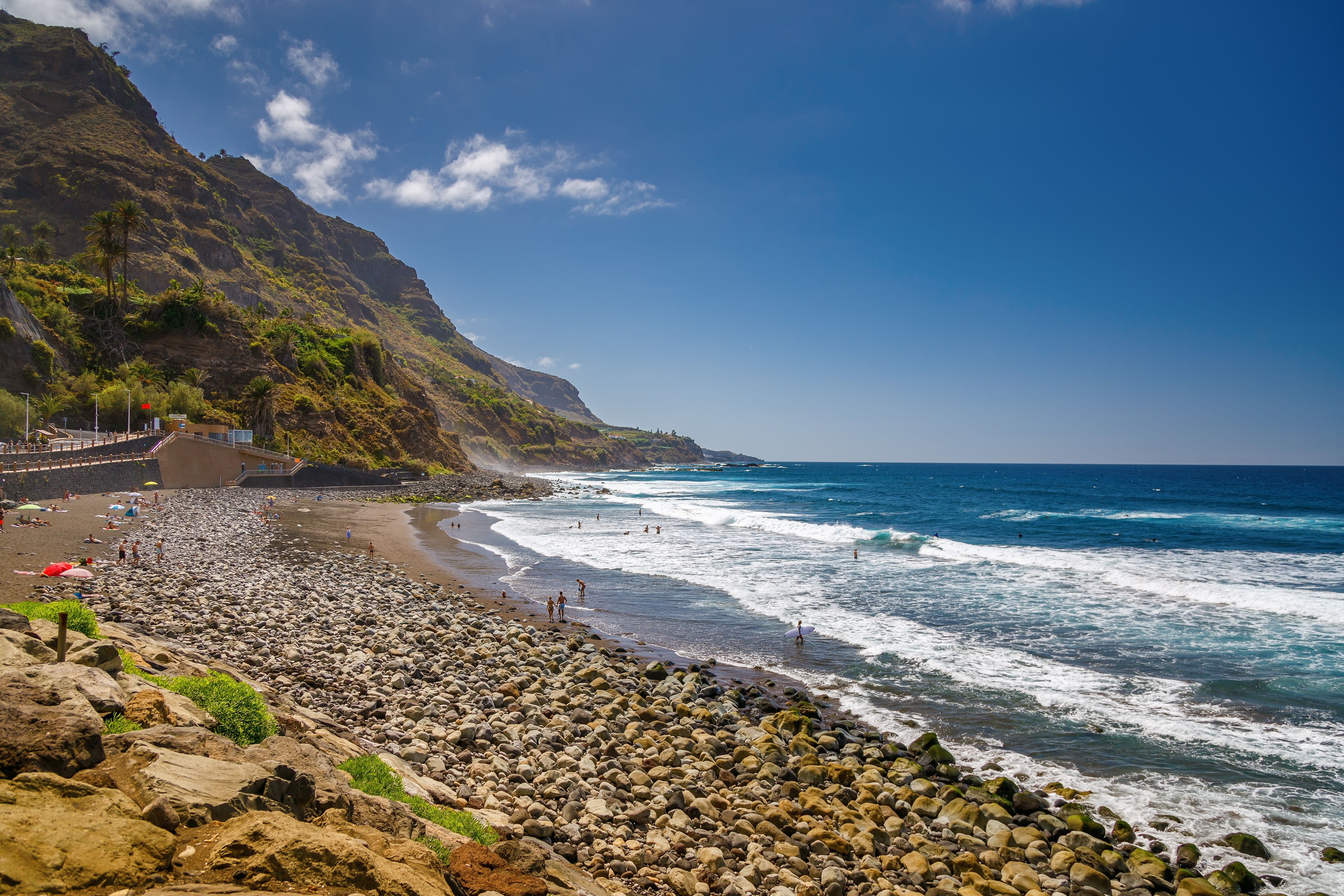 View of a rocky beach tucked beneath towering cliffs and battered by waves.