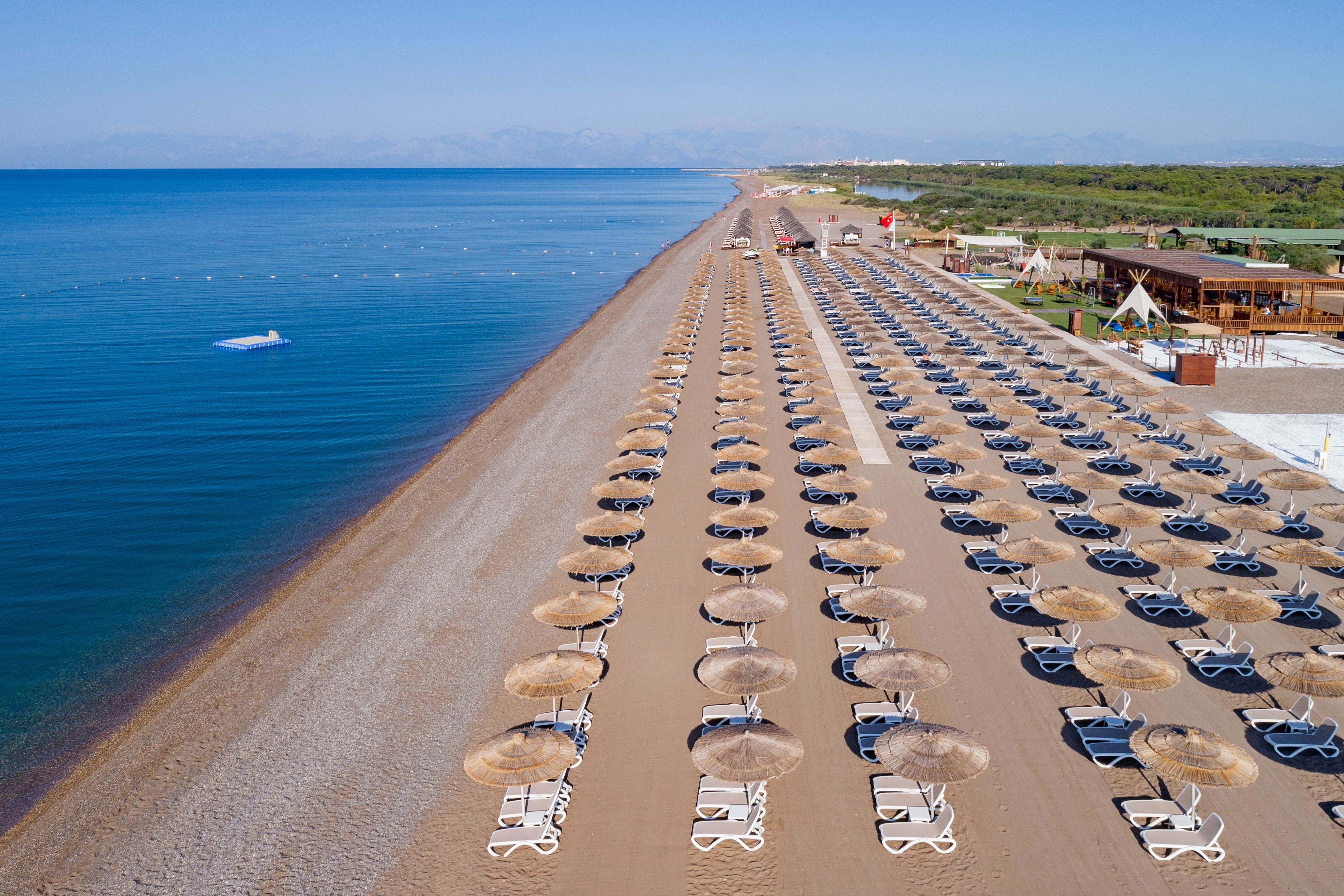 A view of sun loungers and umbrellas on a beach in Belek, Turkey on a clear blue day