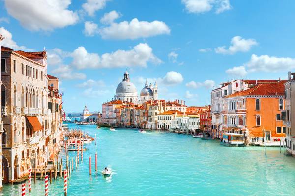 A view of the houses and basilica on Venice's Grand Canal with fluffy white clouds in the sky