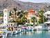 View of boats bobbing in the marina of a Greek island town with a bell tower and red-domed church in the background