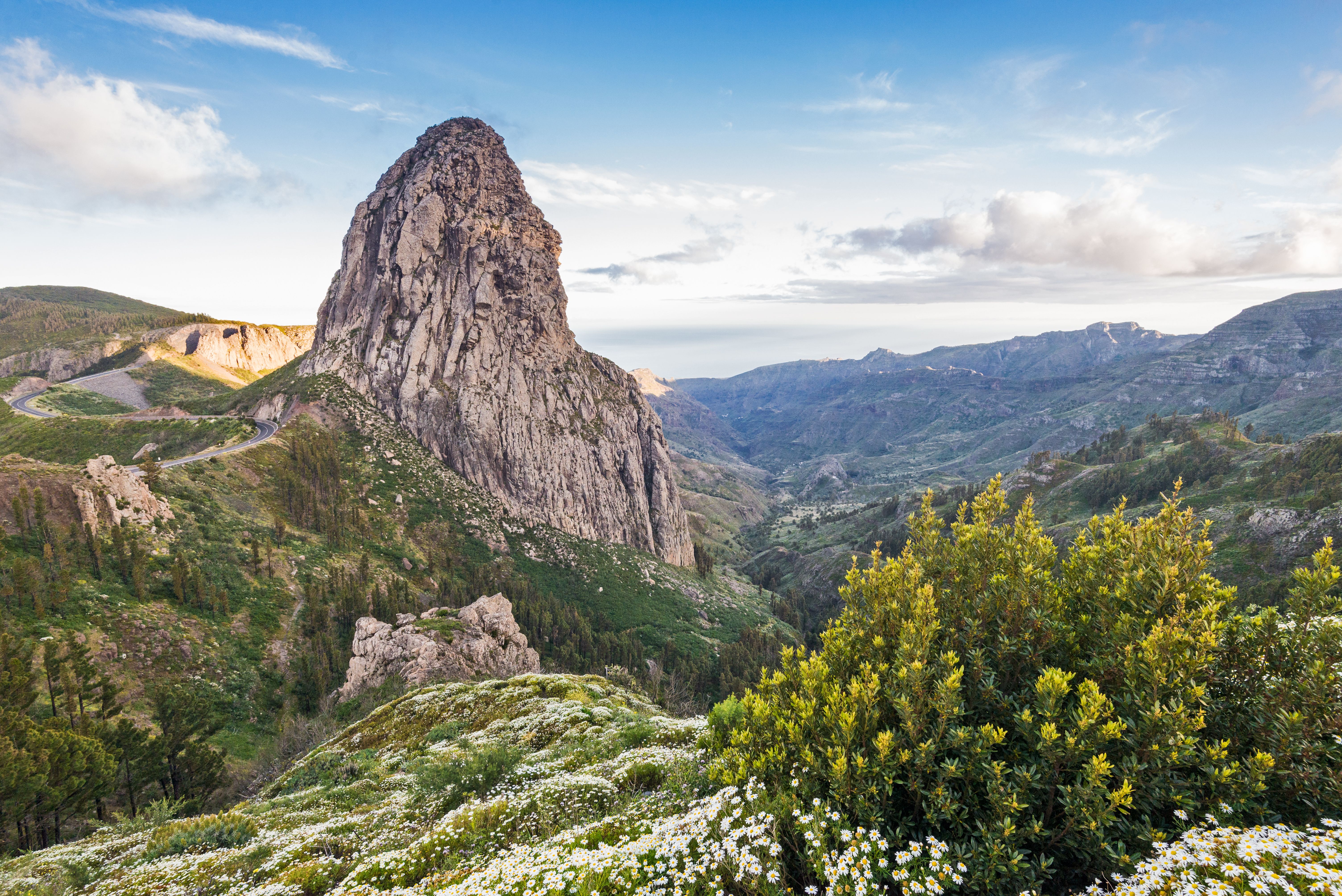 View of Roque Agando rising above a green valley with flowers in La Gomera