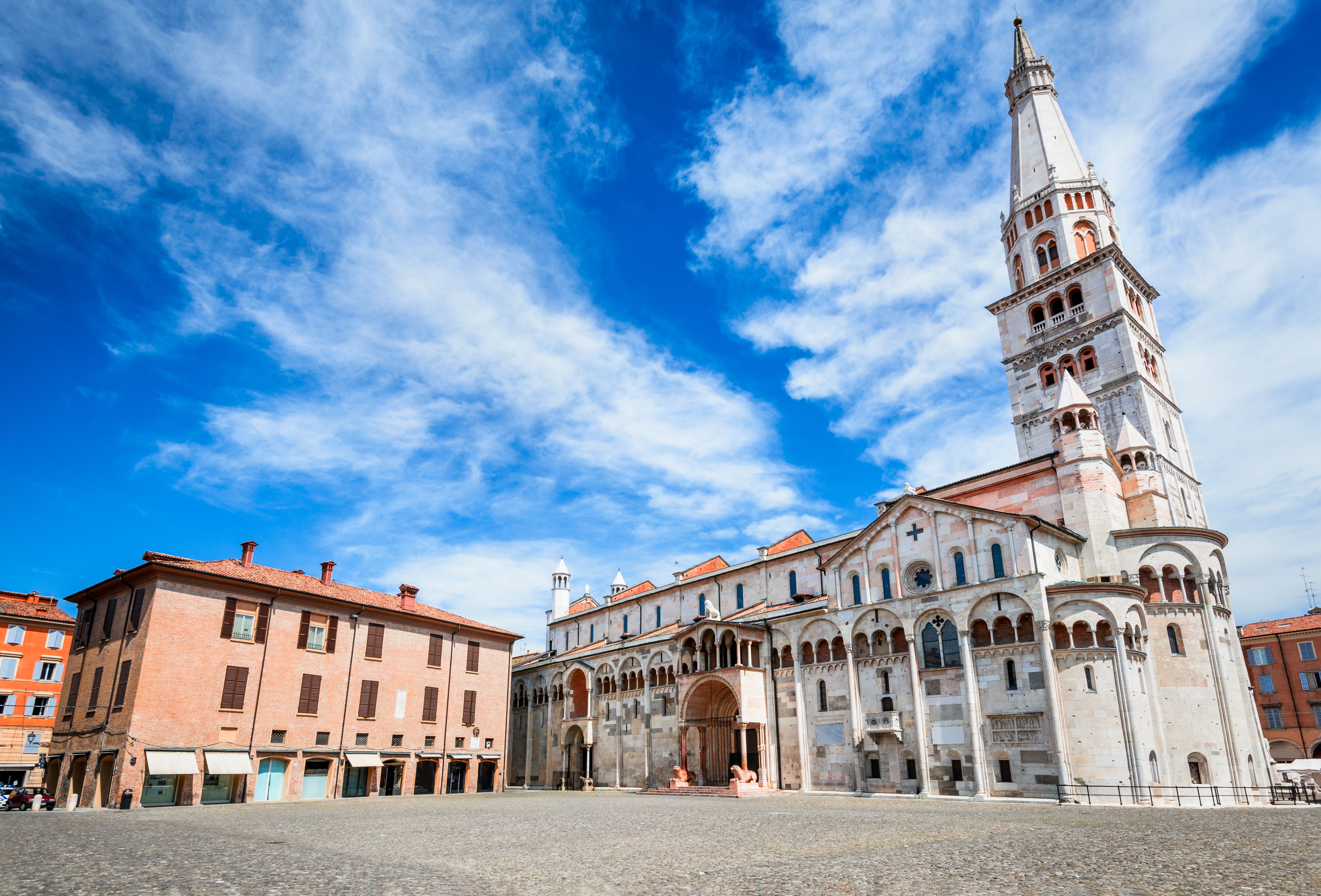 View of an empty town square with a towering whitewashed cathedral and sun-bleached pastel houses