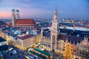 Aerial view of Munich's intricate town hall and a two-towered gothic church with Christmas markets in the Marienplatz square below