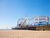 View of a fairground with a ferris wheel and small rollercoaster on the Santa Monica Beach.