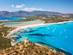 Aerial view of Porto Giunco beach in Sardinia with turquoise bays, white sand and mountains in the distance