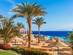 A beach with palm trees and thatched umbrellas in Sharm el Sheikh, Egypt