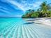 A typical tropical scene of crystal clear waters lapping white sands fringed by palm trees