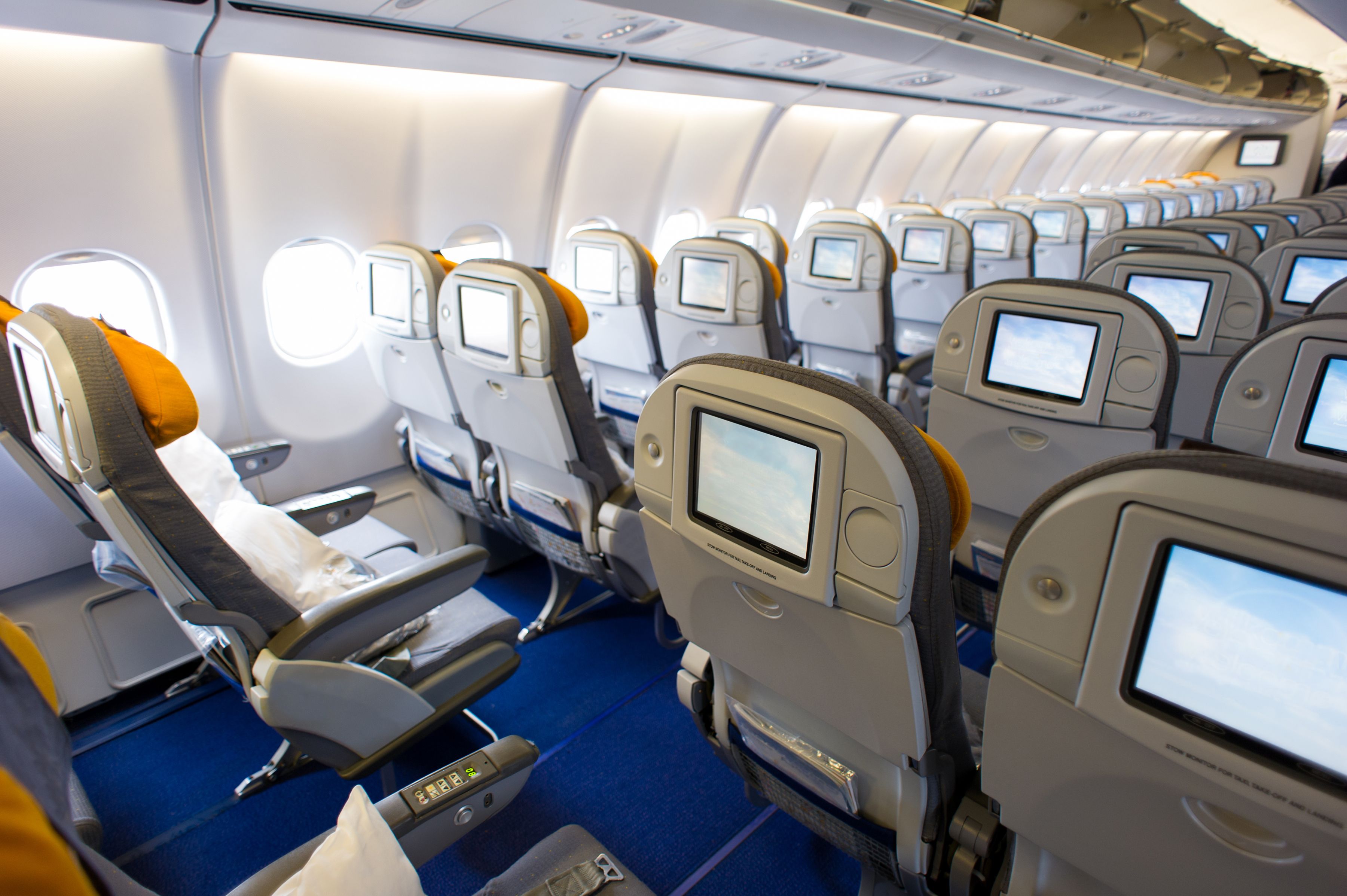 Interior view of an empty plane with tv screens for each passenger seat