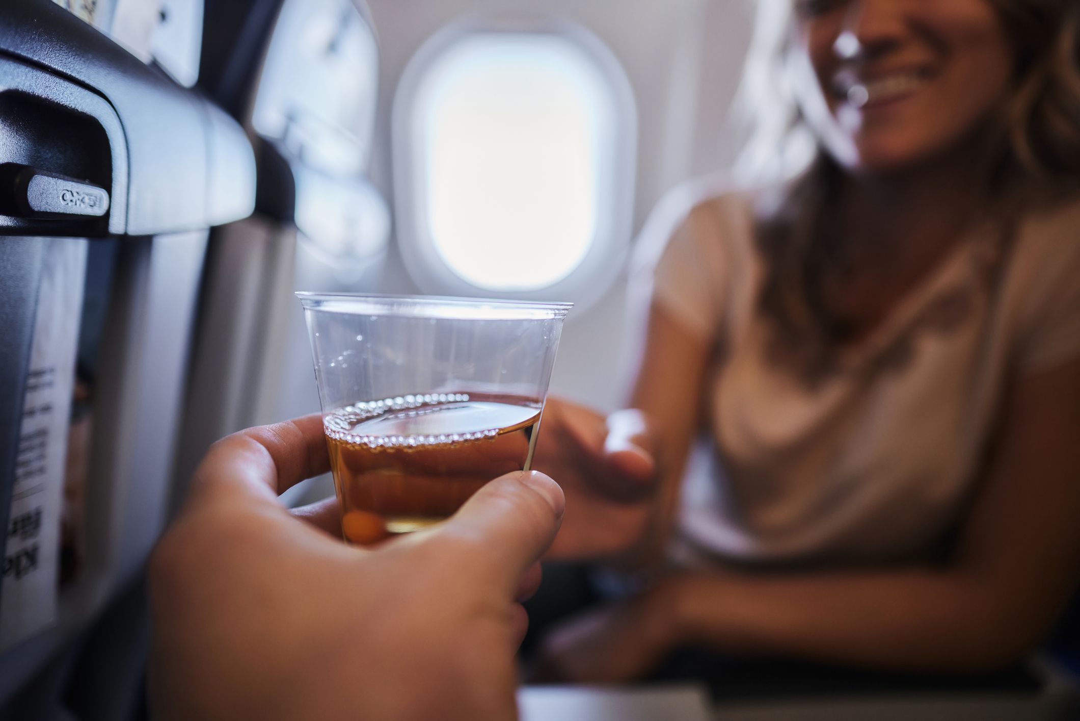 Two people passing a drink to one another on a plane