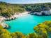 Aerial view of Cala Mitjana beach in Menorca with clear blue water and people swimming, located in the Balearic Islands of Spain