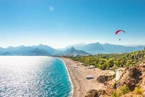 An aerial panoramic view of Antalya and Mediterranean seacoast and beach with a paraglider in Turkey on a sunny summer day with a busy beach