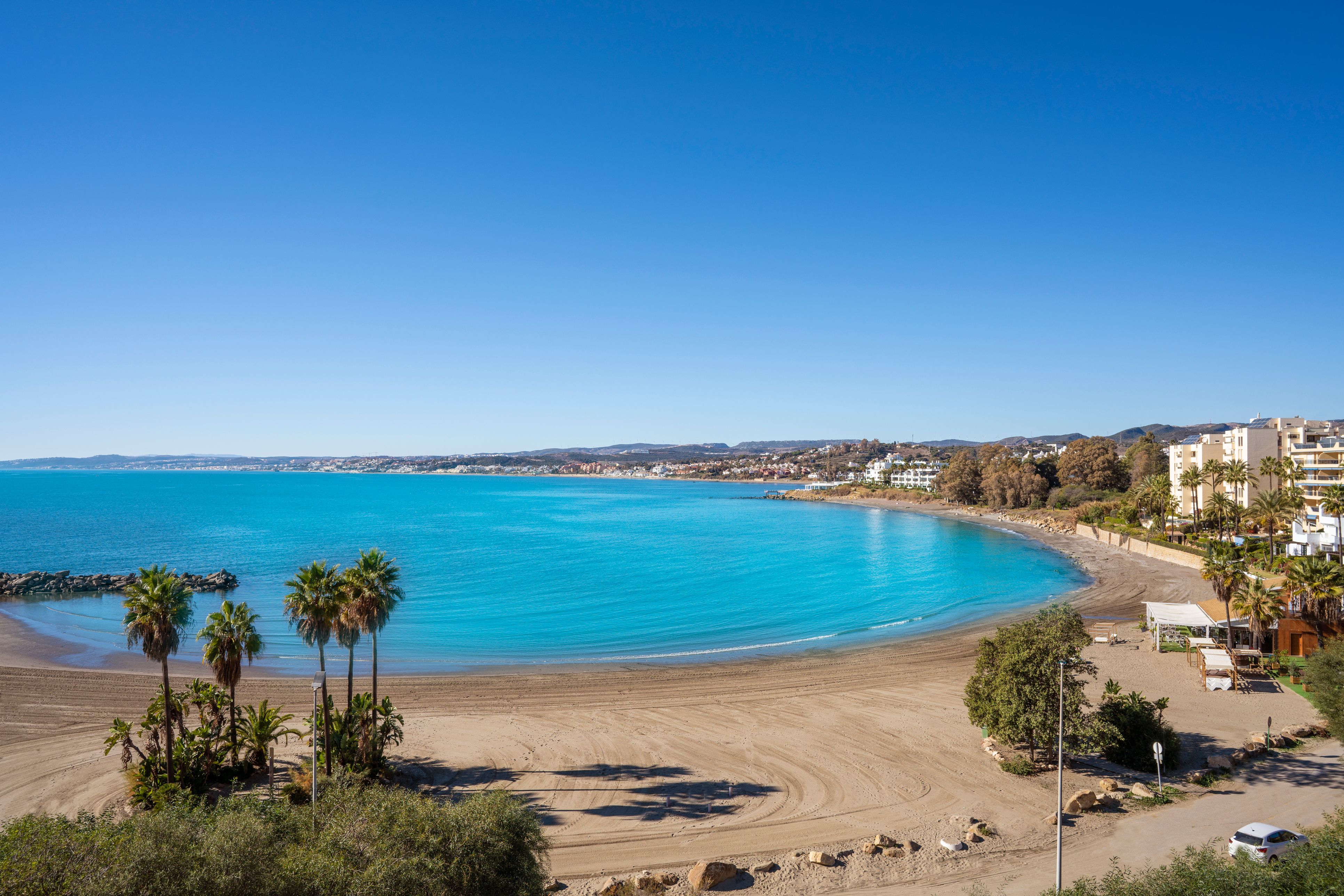 View of an empty horseshoe-shaped beach on a sunny day in Spain