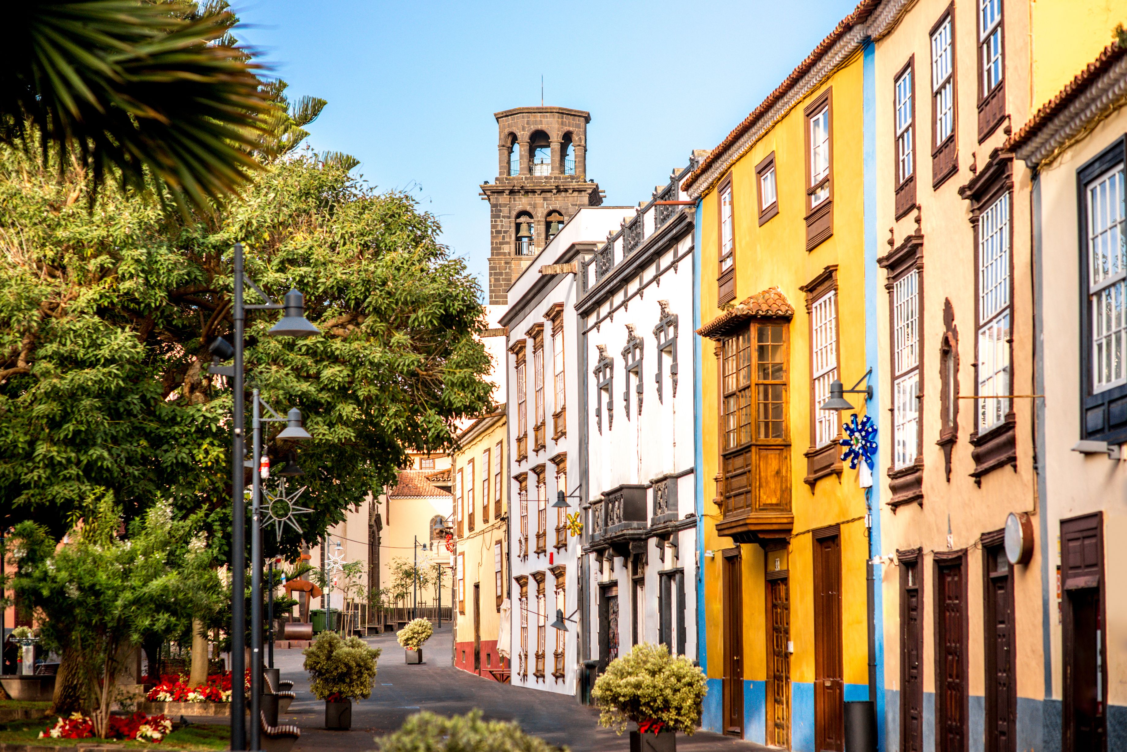 View down a colourful street with a church bell tower poking out from the top of the building at the far end.