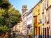 View down a colourful street with a church bell tower poking out from the top of the building at the far end.