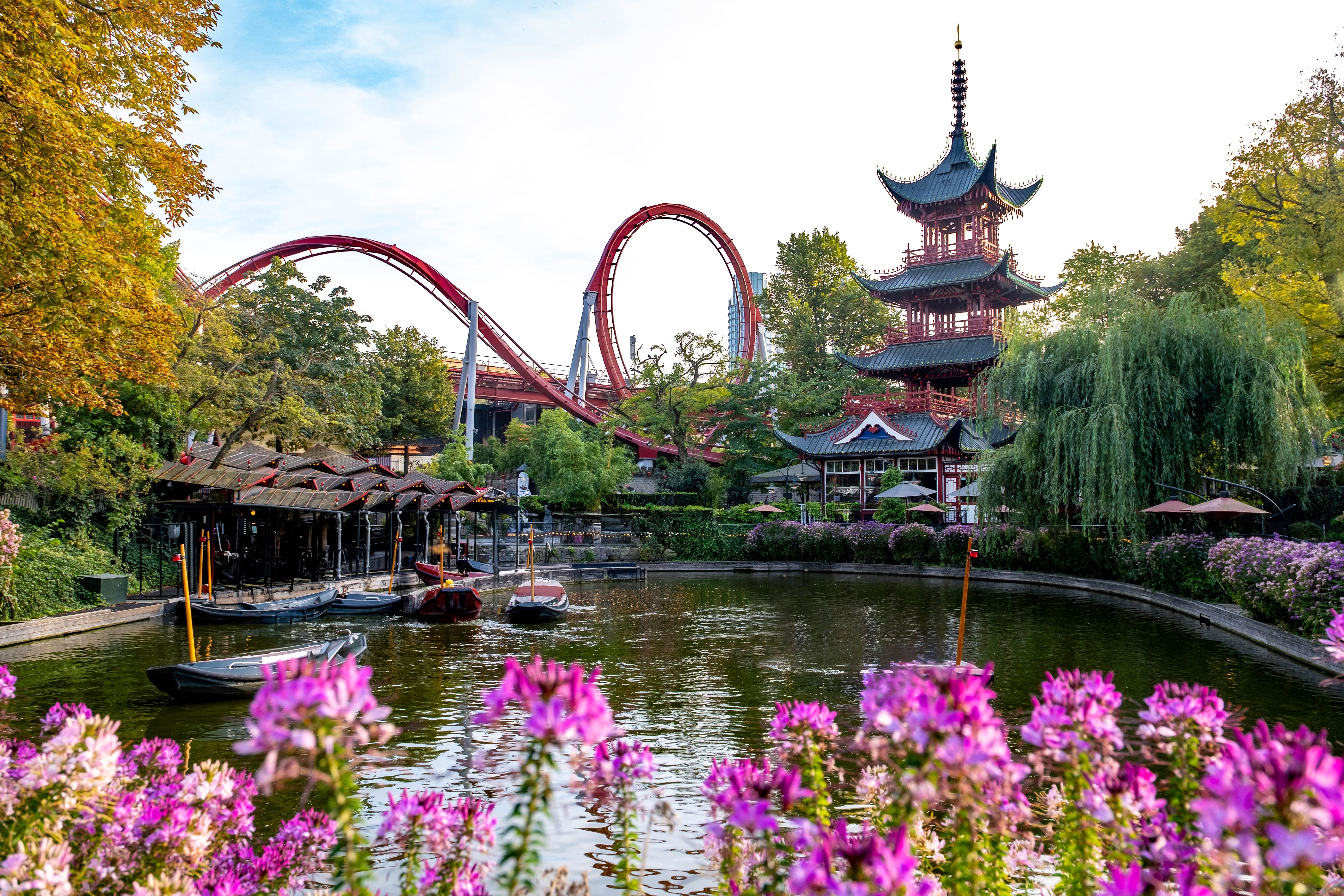 A view of a lake and rollercoaster ride in Tivoli gardens, Copenhagen