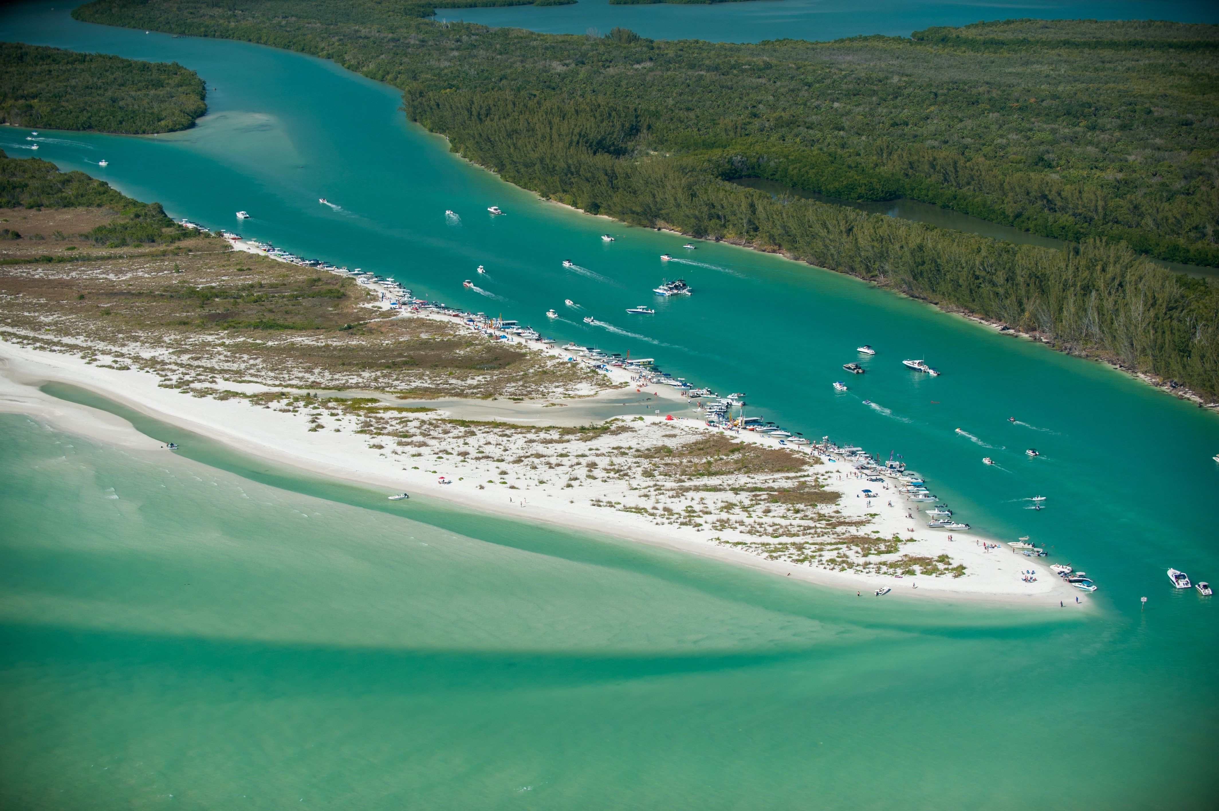 Aerial view of boats along a narrow channel of blue-green water between islands