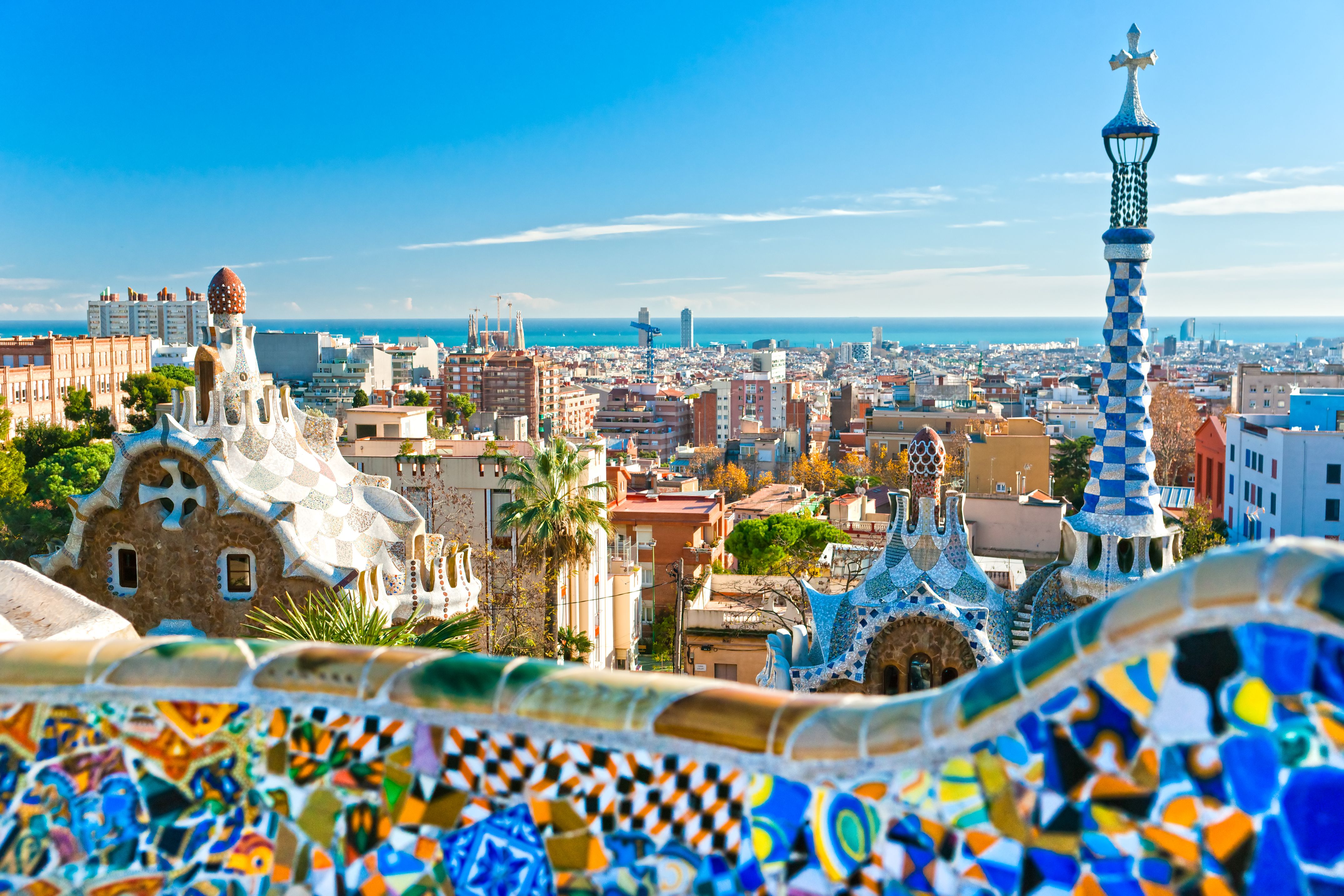A view of Park Guell in Barcelona with brightly coloured mosaic buildings on a bright blue day