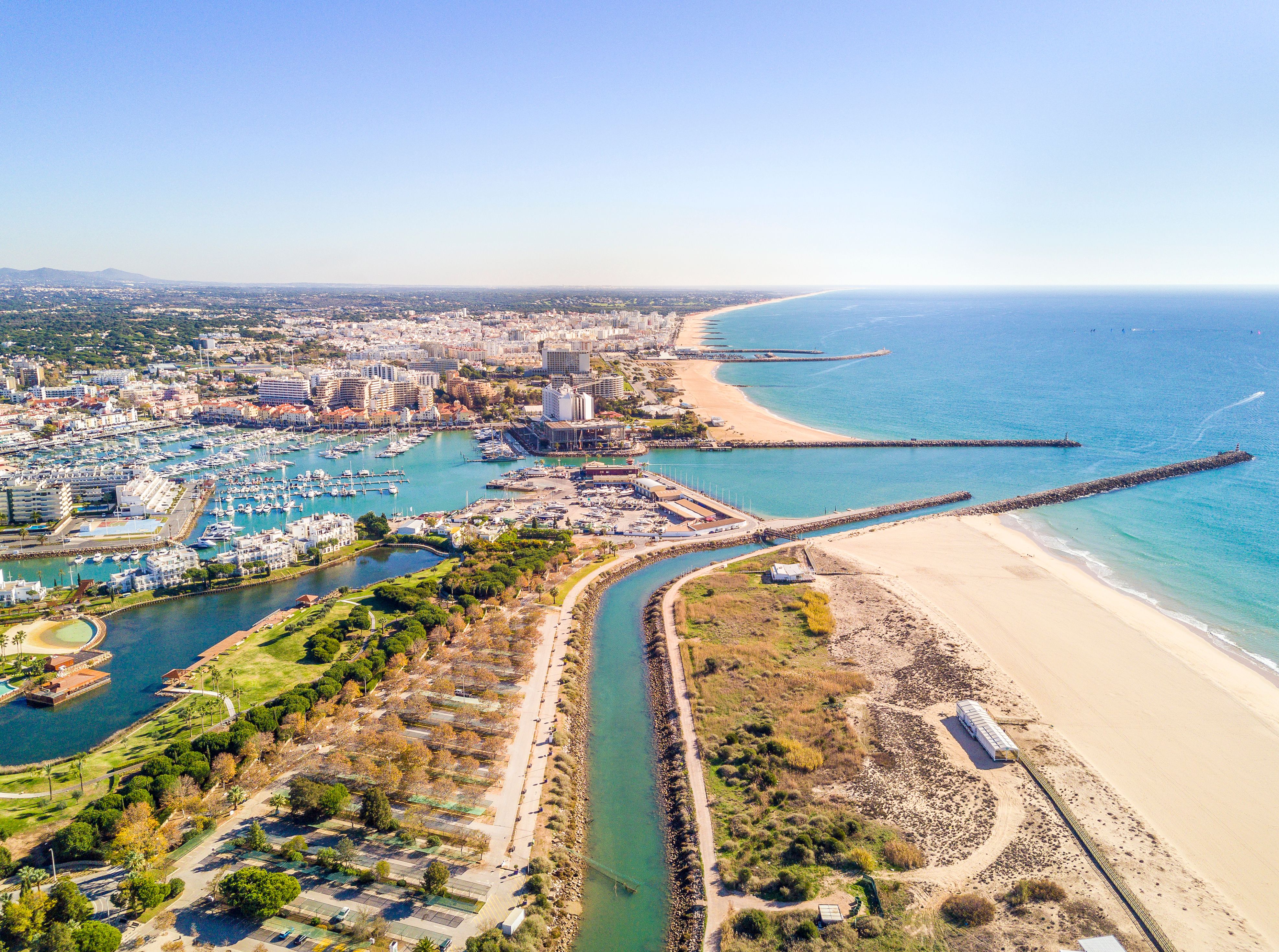 Aerial view of the beach town of Vilamoura in Portugal, with it marina, golden beaches and a river that feeds into the Atlantic.