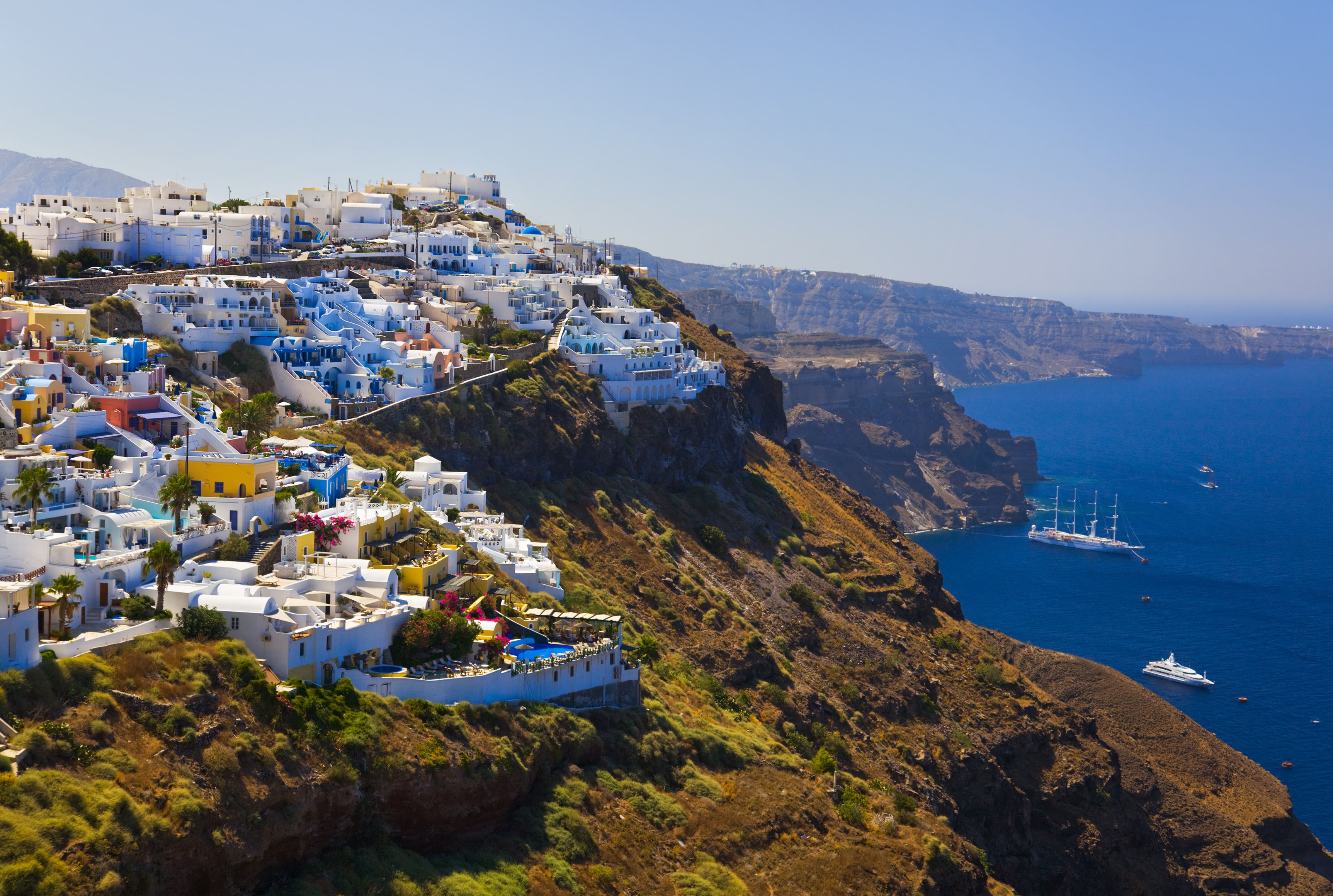 A whitewashed village clings to the side of a steep cliff overlooking the Mediterranean
