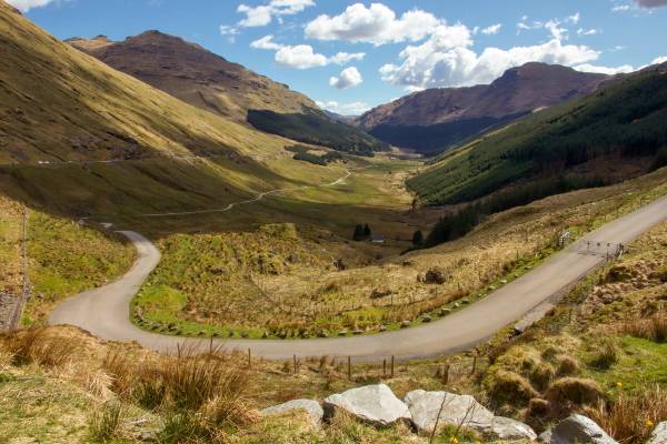 A looping road runs through the green mountains of Glen Coe in the Scottish Highlands