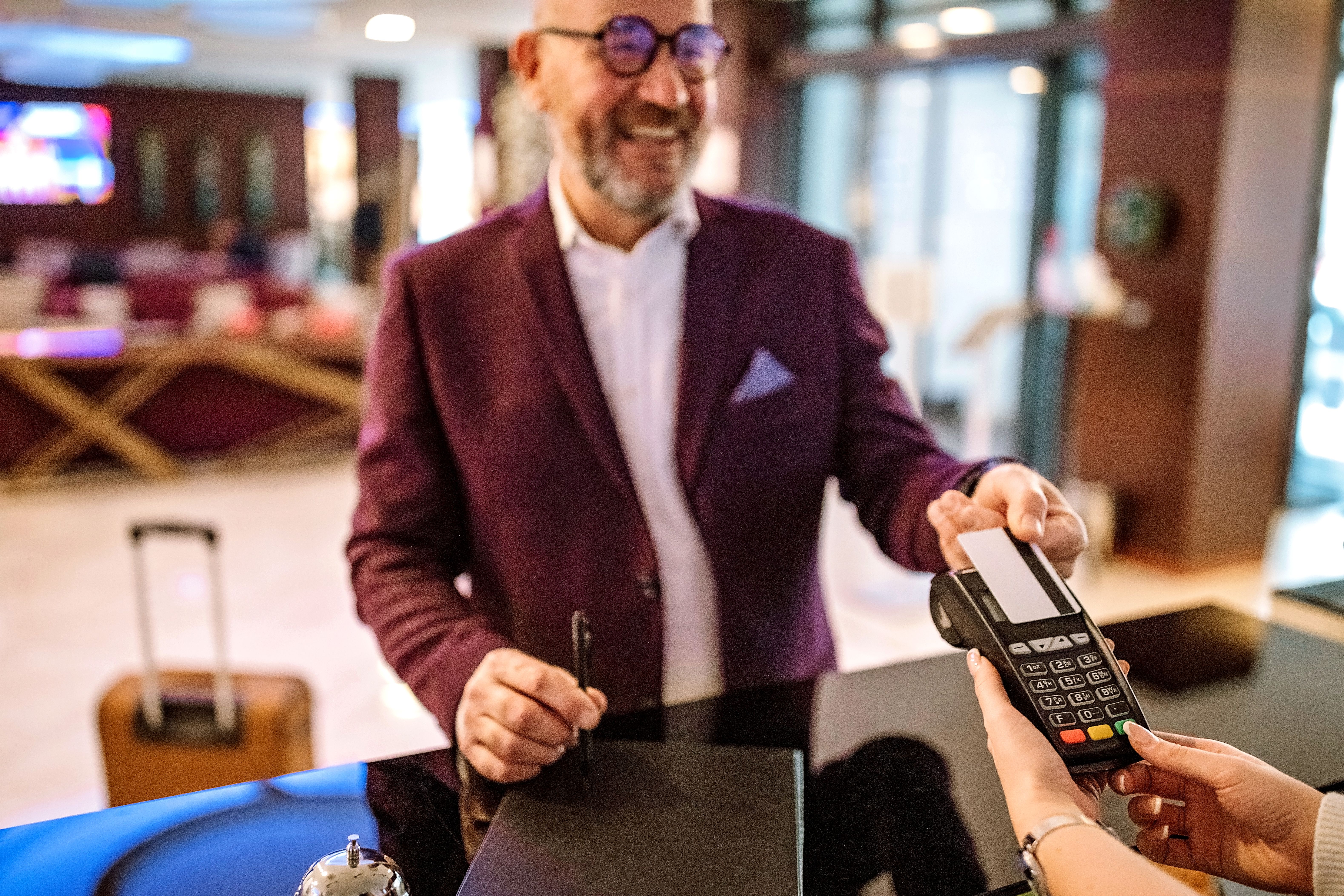A businessman checking out from hotel and making a contactless payment with his credit card