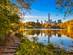 View across a still lake in Central Park with New York's high rises in the background.