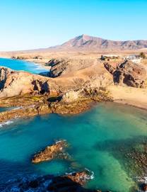 Famous bays and rock formations of Playa de Papagayo Beach in Lanzarote on a sunny, cloudless day
