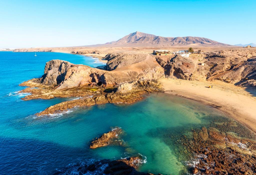 Famous bays and rock formations of Playa de Papagayo Beach in Lanzarote on a sunny, cloudless day