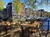 Restaurant tables lining the beautiful canals of Amsterdam under blue skies during springtime, Netherlands