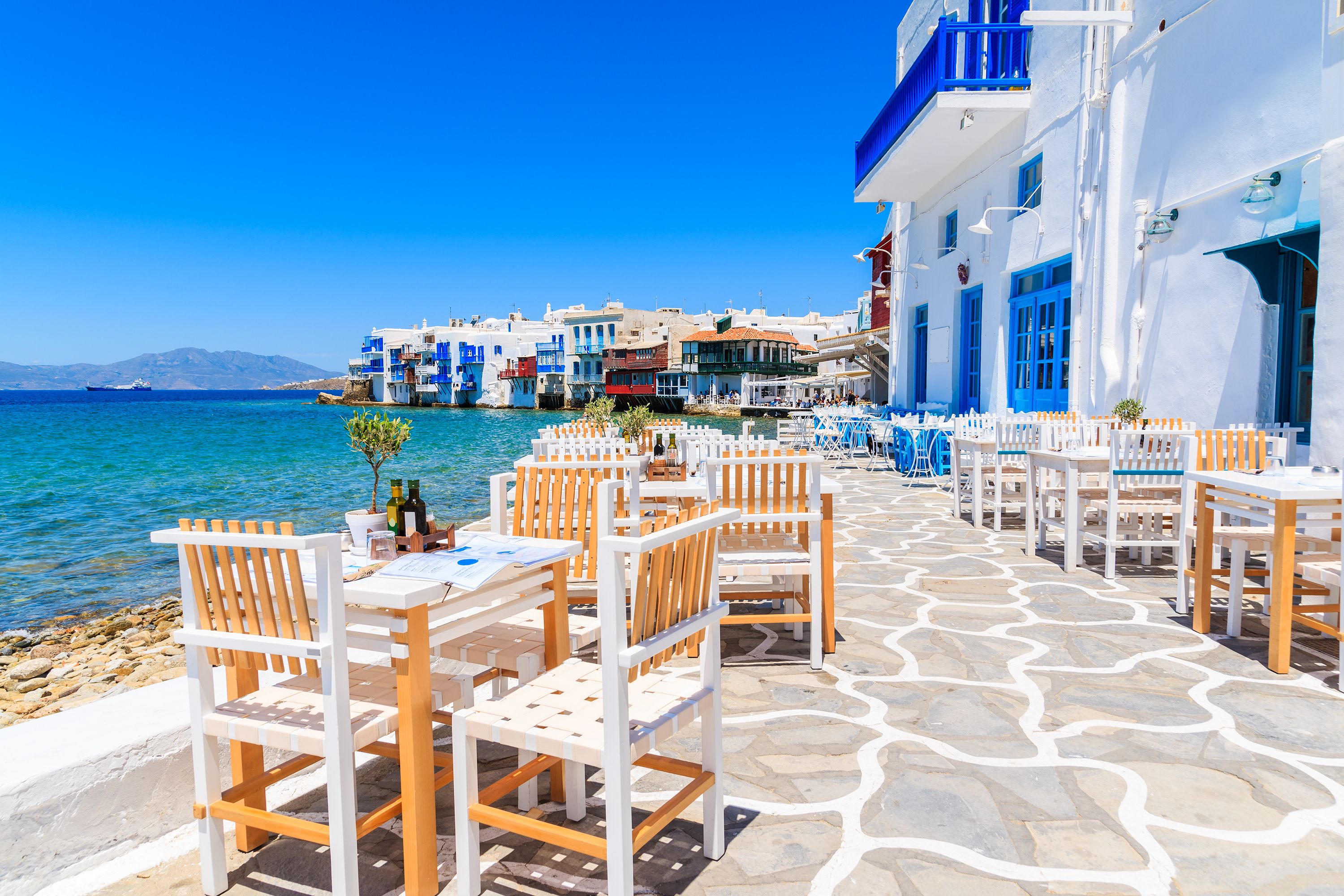 Tables and chairs of a waterfront restaurant in Mykonos town, Greece