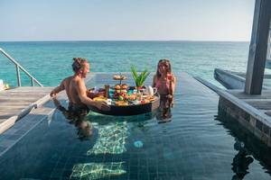 Couple enjoying floating breakfast in private overwater bungalow stock photo