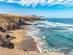 Sweeping view of the wild waves and golden sand of Playa del Viejo Rey beach, which is surrounded by rocky mountains