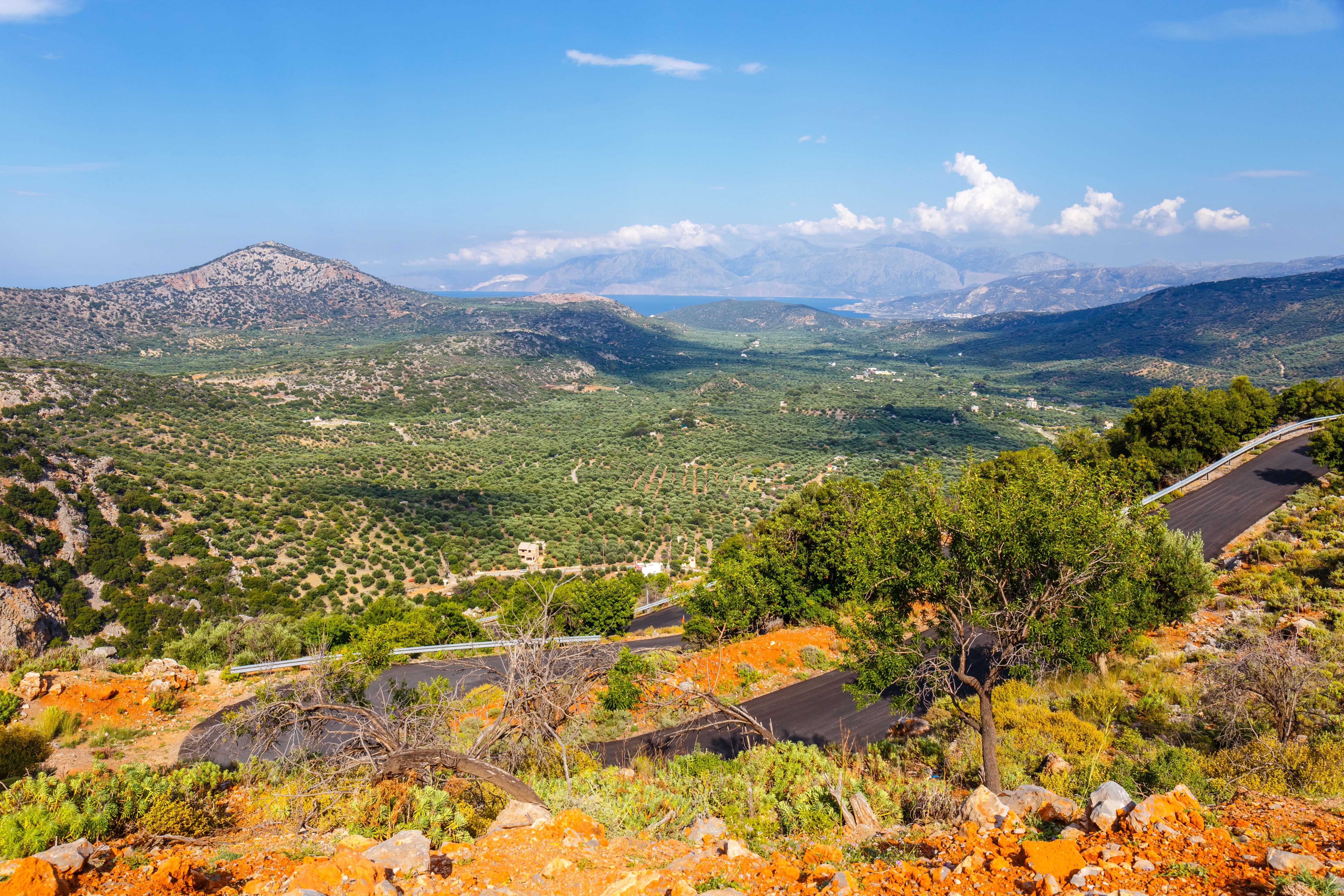 View of a road winding down a mountain with a lush green valley beyond.