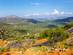 View of a road winding down a mountain with a lush green valley beyond.