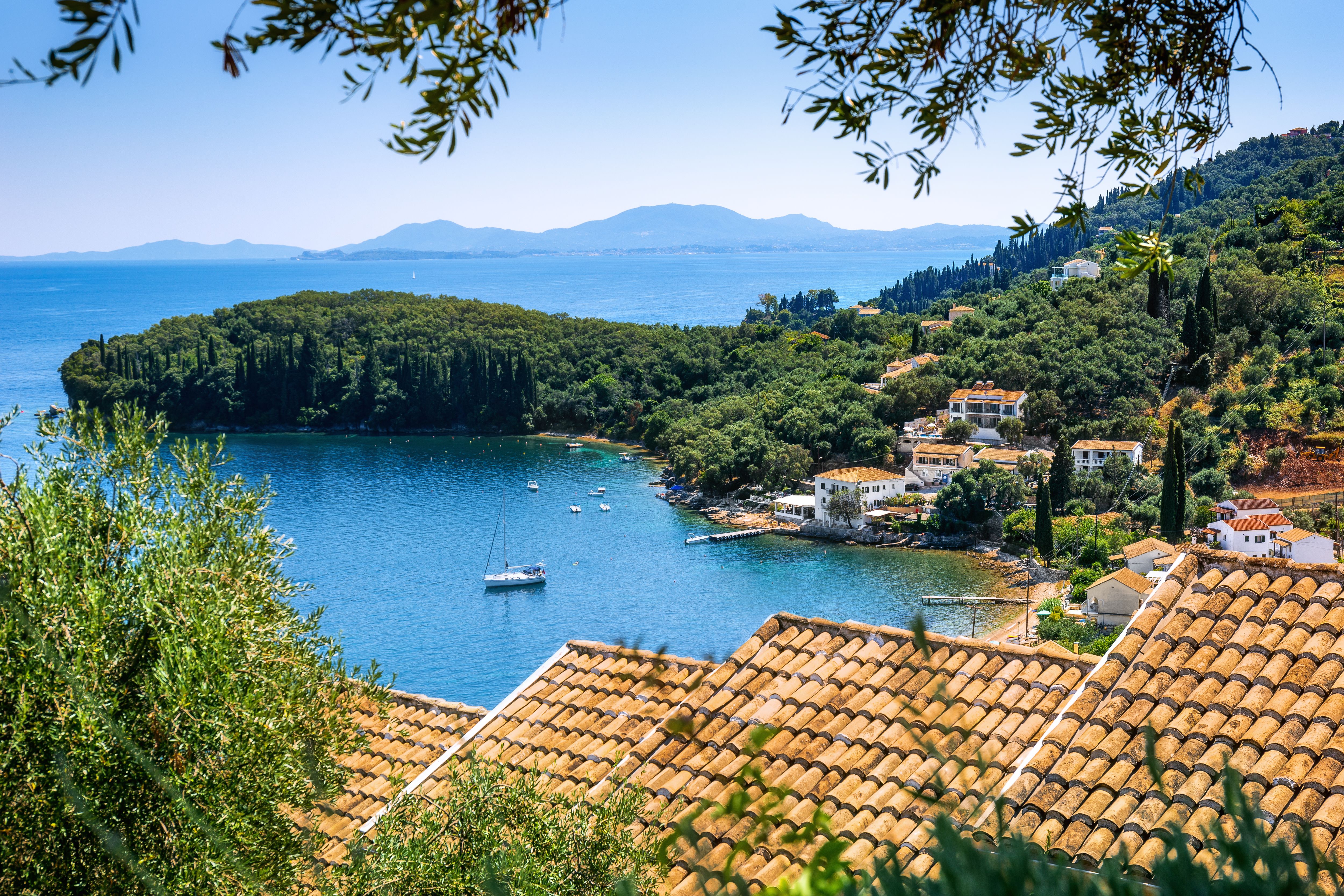 View of a quiet bay scattered with a handful of whitewashed houses and covered in lush greenery.