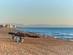 View of a cluster of thatched beach parasols on an empty, sandy beach at sunrise