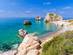 A view of a beautiful beach and sea bay with the rock of Aphrodite in Paphos, Cyprus on a sunny day with clear blue water